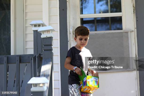 Rosie Lohman carries a box of chalk outside her home Sept. 15 in Milwaukee. Rosie, who has congenital adrenal hyperplasia, is one of a growing number...