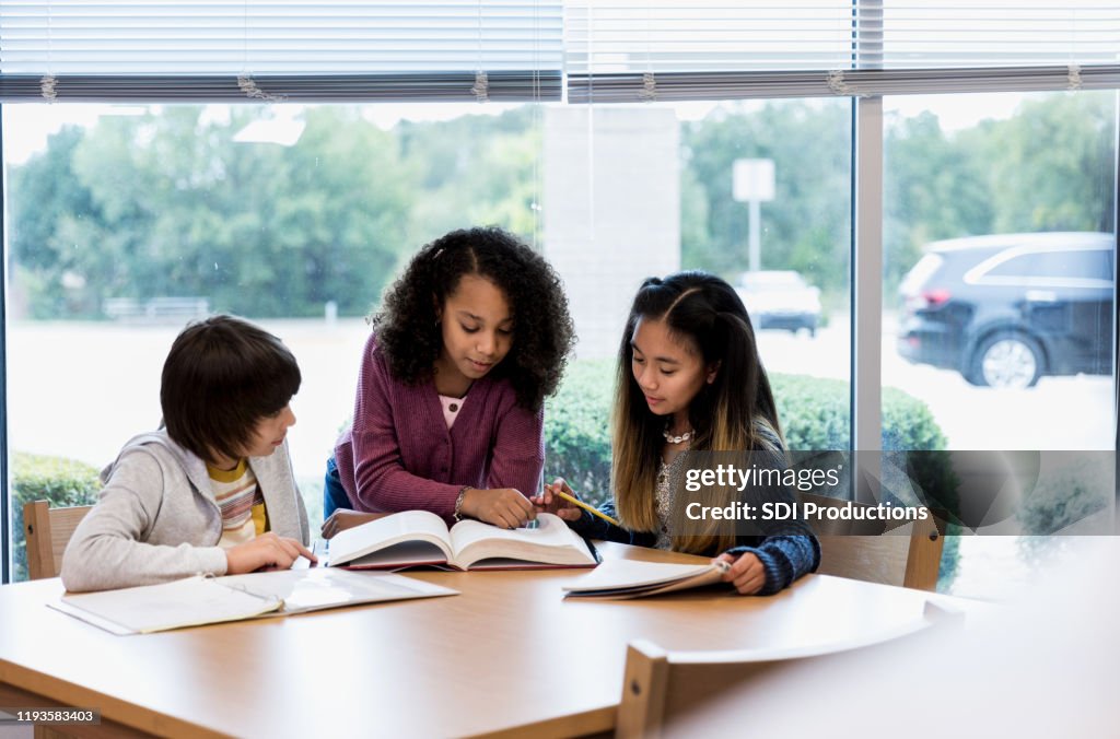 Tre studenti delle scuole medie letti dal libro della biblioteca per il progetto