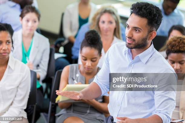 male reporter asks questions during town hall meeting - diverse town hall meeting stock pictures, royalty-free photos & images