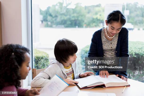 middle school students reading from textbook - history textbook stock pictures, royalty-free photos & images