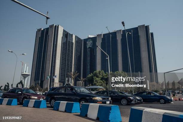 Automobiles drive past the headquarters of the Nigerian central bank in Abuja, Nigeria, on Friday, Jan. 10, 2020. Revenue in Nigeria has fallen short...