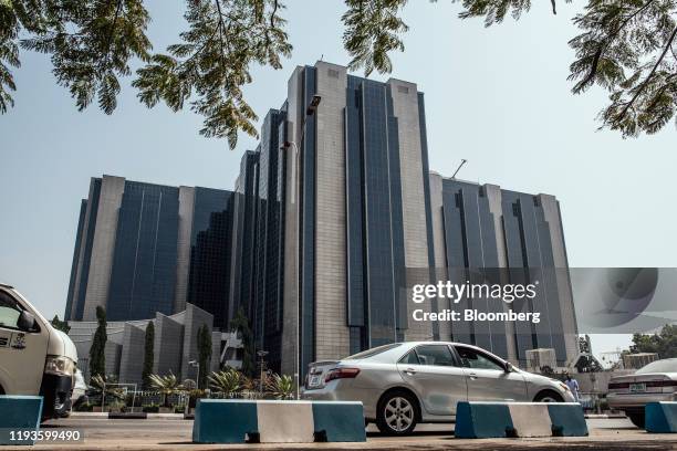 Automobiles drive past the headquarters of the Nigerian central bank in Abuja, Nigeria, on Friday, Jan. 10, 2020. Revenue in Nigeria has fallen short...