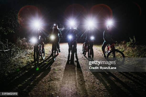 silhouette des women es mountain biking club auf nachtfahrt - dark forest stock-fotos und bilder