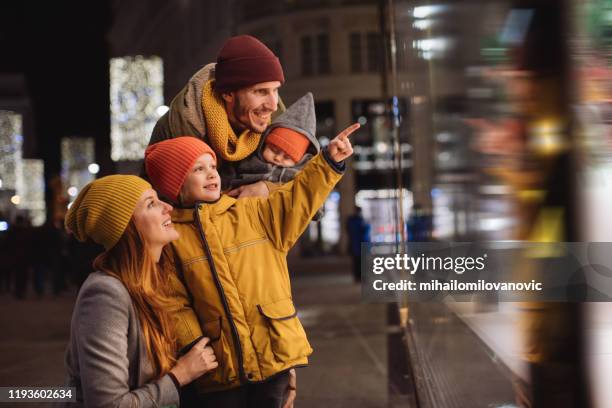 familie mit einem zeigen auf daspausenfenster - schaufensterbummel stock-fotos und bilder