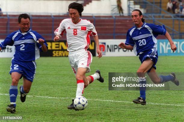 Chinese midfielder Li Tie passes between Guam players Richard Lai and Thomas Quigley during a qualifying match of the Asian Soccer Cup 2000 in Ho Chi...