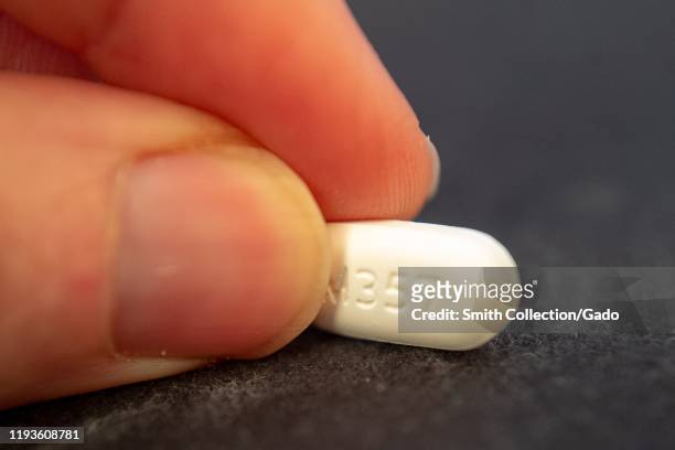 Illustrative image, close-up of hand of a man holding a pill of the combination narcotic opioid pain medication hydrocodone 5-acetaminophen 500,...