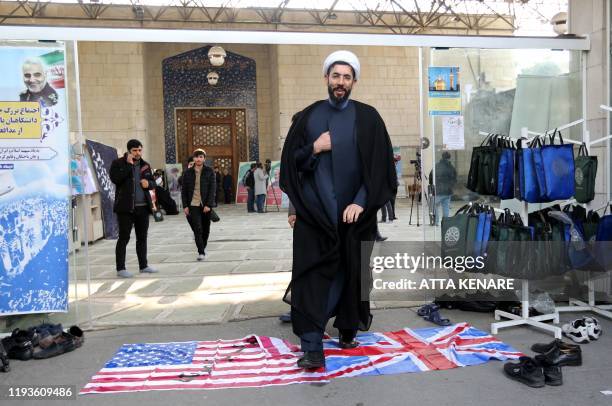Member of the Basij, a militia loyal to the Islamic republic's establishment, walks over a Union Jack and US flag as he arrives at a memorial for...