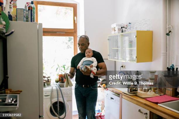 Dad At Home In Kitchen Holding Young Baby