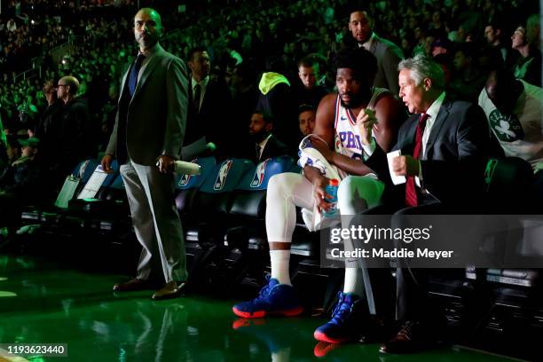 Brett Brown of the Philadelphia 76ers talks with Joel Embiid before the game against the Boston Celtics at TD Garden on December 12, 2019 in Boston,...