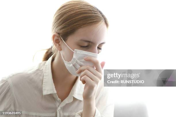 young woman wearing flu mask and cough - tokyo covered by haze stockfoto's en -beelden