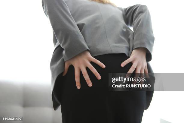 woman with pain in buttocks - fart stock-fotos und bilder