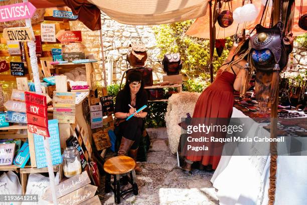 Hippie young women at their crafts street stalls in the market during the Medieval Festival.