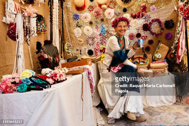 Hippie young woman sits at her crafts street stall in the market during the Medieval Festival.