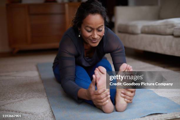 sonriente mujer madura practicando su sentada hacia adelante pos de la curva - tocar los dedos de los pies fotografías e imágenes de stock