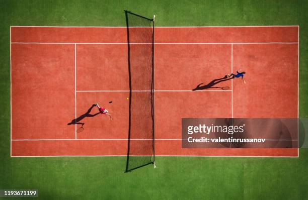 drohnenansicht des tennisspiels von oben mit spielerschatten - tennis stock-fotos und bilder