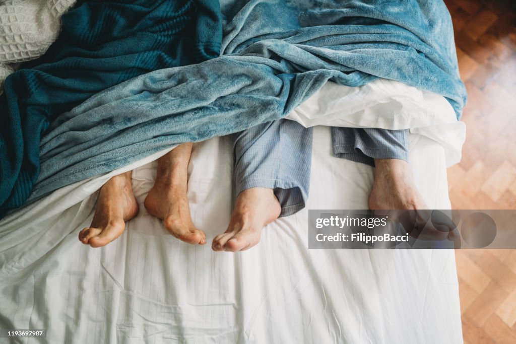 High angle view of feet lying down in bed