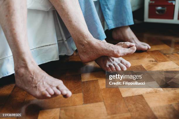 zijaanzicht van de voeten van een senior paar aan de zijkant van bed - old lady feet stockfoto's en -beelden