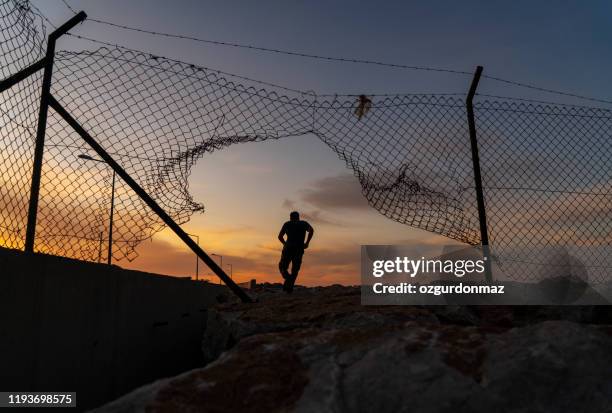 refugee man running behind fence, - saída imagens e fotografias de stock