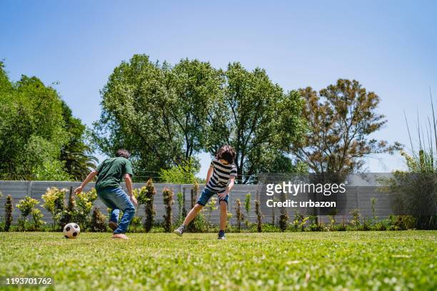 kinder, die im hinterhof fußball spielen - backyard football stock-fotos und bilder