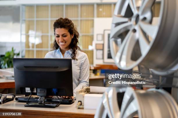 hermosa mujer que trabaja en la recepción de un taller de reparación de automóviles mirando la pantalla de la computadora muy alegremente - repuesto fotografías e imágenes de stock