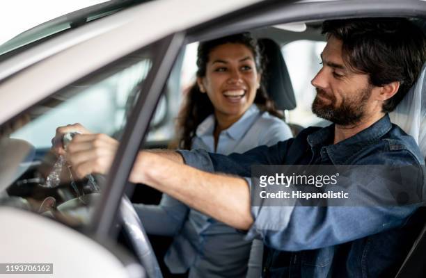 excited young couple shopping for a new car trying it out talking and smiling - buying a car stock pictures, royalty-free photos & images