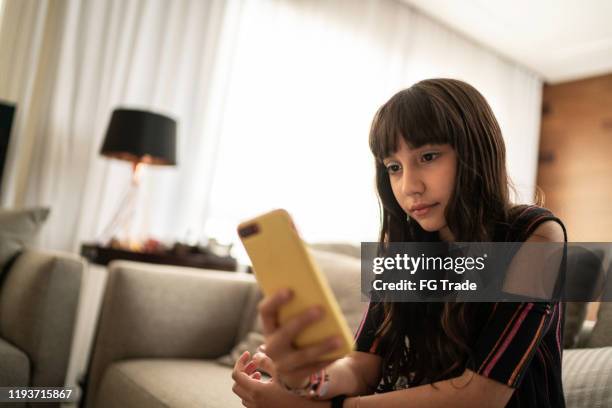 klein meisje liggend op de bank met behulp van mobiele thuis - chat noel stockfoto's en -beelden