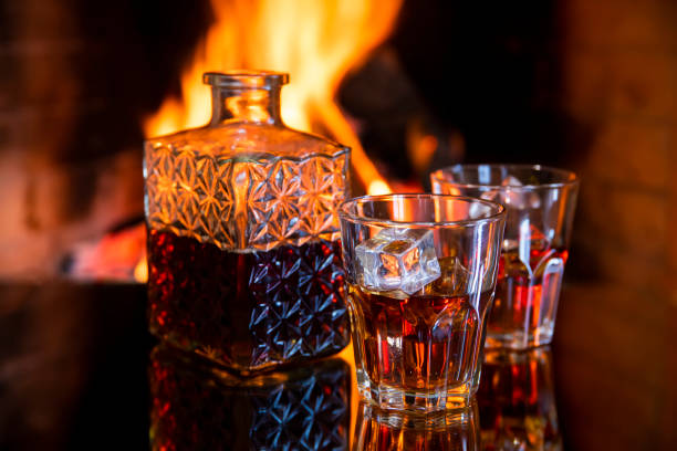 two glasses and a of whiskey near the fireplace
