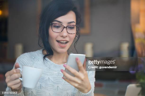 verbaasd vrouw controleren telefoon vinden goed nieuws - vinden stockfoto's en -beelden