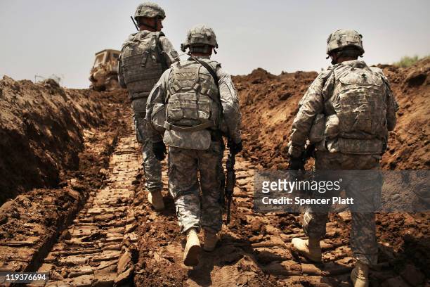 Soldiers with the 3rd Armored Cavalry Regiment patrol a new ditch they have dug to protect the base from attack on July 19, 2011 in Iskandariya,...