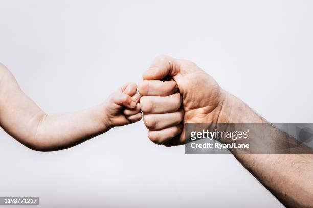 mano del bebé dando golpe de puño a la mano de los padres - fist bump fotografías e imágenes de stock