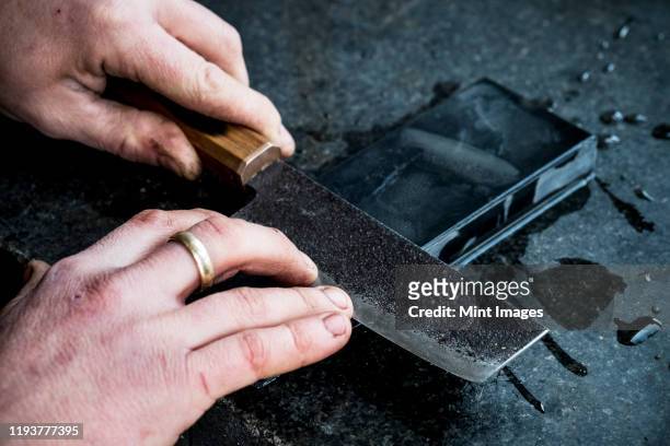 high angle close up of person sharpening handmade knife on a whetstone. - sharpening stock-fotos und bilder