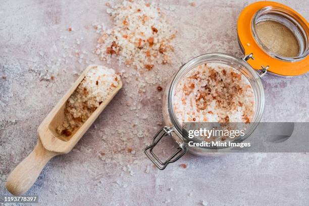 high angle close up of wooden spoon and glass jar with coarse salt. - bath salt stock pictures, royalty-free photos & images