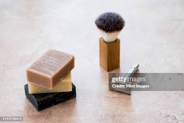 high angle close up of three bars of homemade bars of soap, shaving brush and razor. - shaving brush stock-fotos und bilder