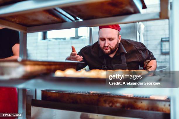 male baker taking in smell from freshly baked pastry - ruined dinner stock pictures, royalty-free photos & images