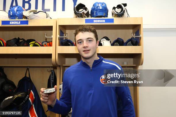 Noah Dobson of the New York Islanders poses for a photo with his first career NHL goal puck following his teams win against the Detroit Red Wings at...