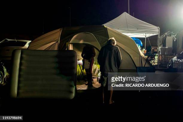 Man stand in front of a camping tent at a tent city shelter at a baseball stadium parking lot in Yauco, Puerto Rico on January 14 after a powerful...