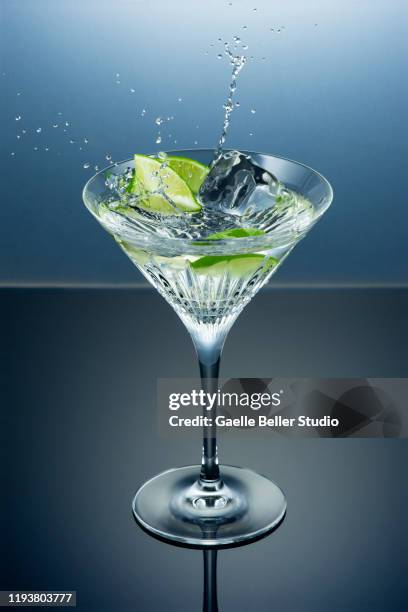 martini cocktail on the rocks with a slice of lime and splashes - gin stock-fotos und bilder