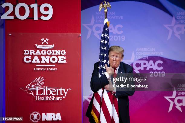 President Donald Trump hugs an American flag before speaking during the Conservative Political Action Conference in National Harbor, Maryland, U.S.,...