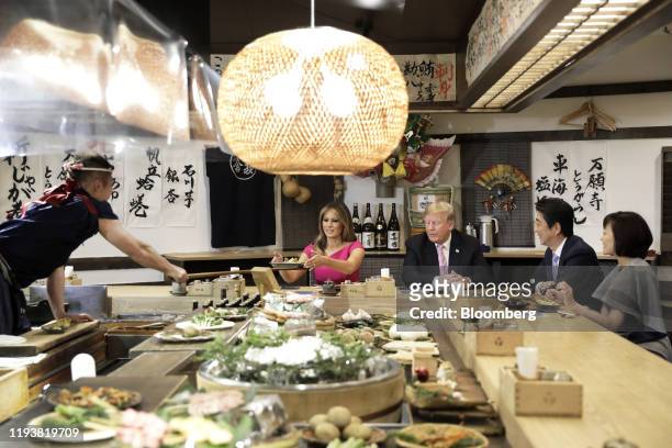 First Lady Melania Trump, second left, is served a baked potato with butter while sitting at a counter with U.S. President Donald Trump, center,...