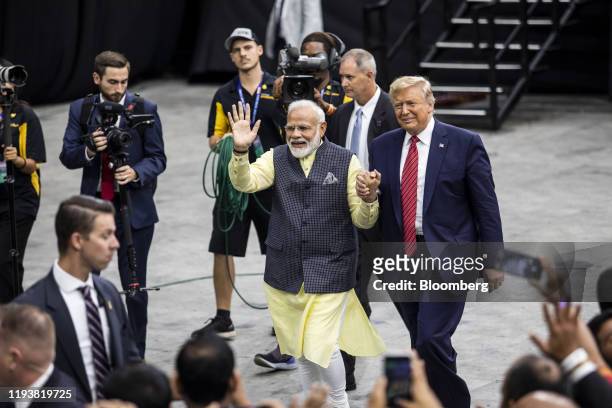 Narendra Modi, India's prime minister, center left, and U.S. President Donald Trump hold hands while leaving the Howdy Modi Community Summit in...