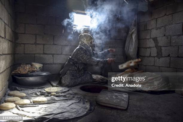 Woman makes bread traditional tandoor oven, which is kind of a cylindrical hole made up of clay or metal, at the kitchen of her house, Mus, Turkey on...