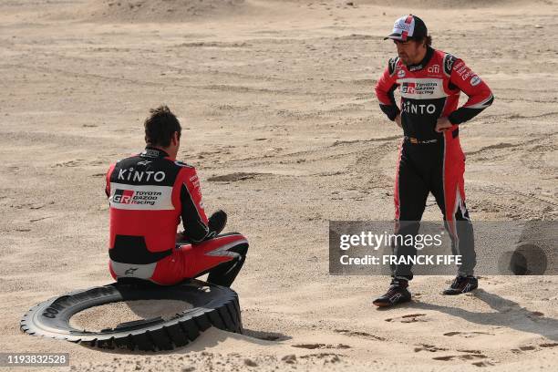 Toyota's Spanish driver Fernando Alonso speaks with Spanish co-driver Marc Coma after the neutralisation of the race due to strong winds during the...