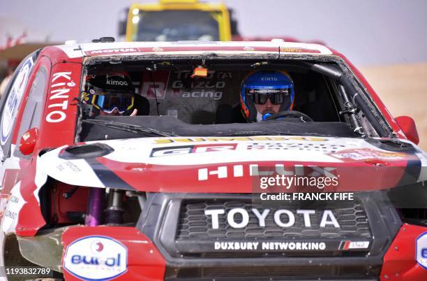 Toyota's Spanish driver Fernando Alonso and and Spanish co-driver Marc Coma drive their car after the neutralisation of the race due to strong winds...