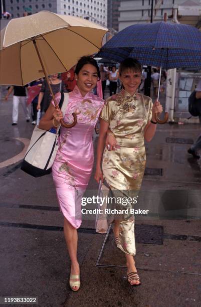 Two Chinese and European women wearing Cheongsam dresses walk through Central, on their way to a handover party on the eve of the handover of...