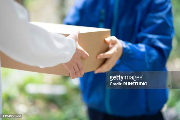 midsection of delivery person delivering box to woman - 宅配便サービス ストックフォトと画像