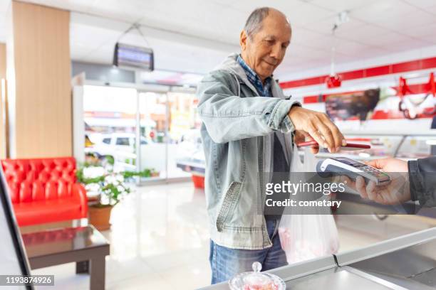 hombre mayor haciendo el pago sin contacto - red meat fotografías e imágenes de stock