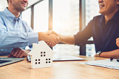 Closeup of real estate broker agent shaking hands with customer after signing contract agreement documents successfully with house property. Ownership realty purchase. Mortgage loan approval concept.
