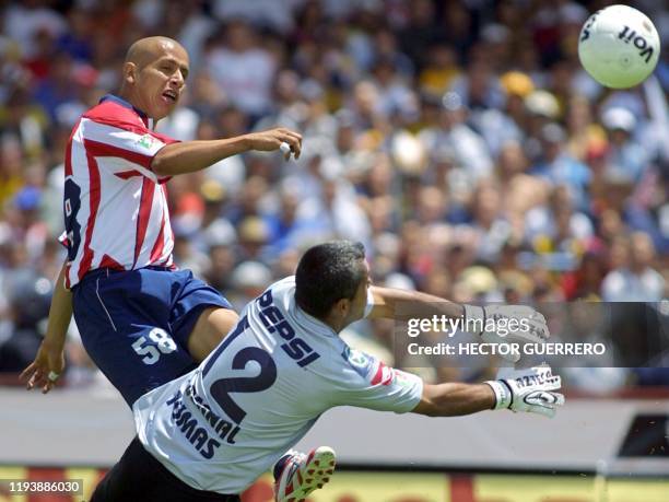 Adolfo Bautista de Chivas patea el balón ante la marca del portero de Pumas Sergio Bernal durante el partido en ciudad de México el 28 de marzo de...