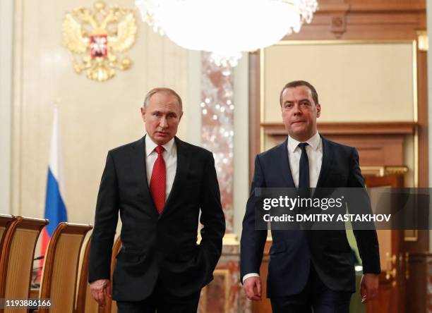 Russian President Vladimir Putin and Prime Minister Dmitry Medvedev walk before a meeting with members of the government in Moscow on January 15,...