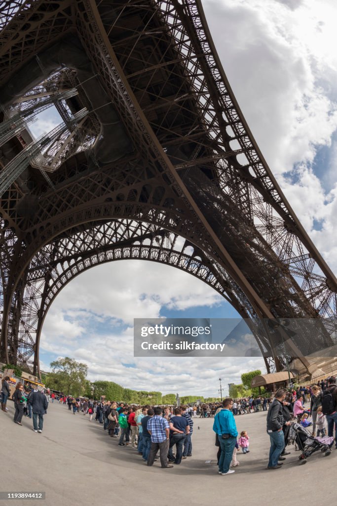 People standing in line to visit the Parisian Eiffel Tower in springtime
